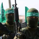 Armed masked men with green flags in military fatigues.