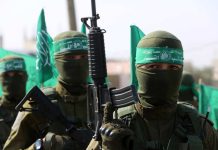 Armed masked men with green flags in military fatigues.