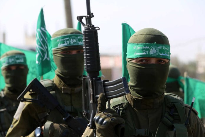 Armed masked men with green flags in military fatigues.