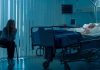 Woman sitting beside hospital bed at night