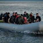 People on a packed raft in open water.