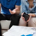 Couple looking at empty wallet and bills