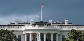 White House with American flag and fountain stormy sky