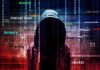 Hooded figure with cybersecurity terms and binary code background