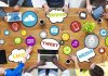 Top view of a collaborative workspace with social media icons and people using laptops