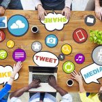 Top view of a collaborative workspace with social media icons and people using laptops