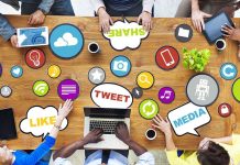 Top view of a collaborative workspace with social media icons and people using laptops