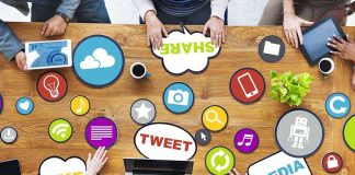 Top view of a collaborative workspace with social media icons and people using laptops