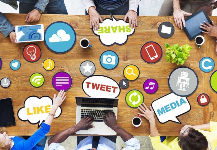 shutterstock_189811238.jpg Top view of a collaborative workspace with social media icons and people using laptops