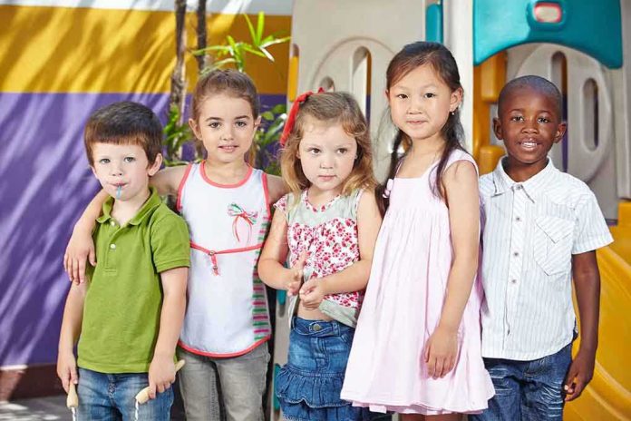 shutterstock_193504529.jpg Five children standing together in a playground setting, smiling at the camera