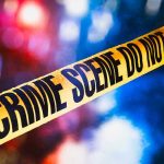 Yellow crime scene tape with blurred lights background.