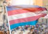 Transgender pride flag waving at outdoor event.