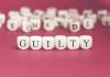 Dice spelling "GUILTY" on a red surface.