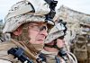 Two soldiers in military gear looking serious in an outdoor setting