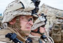 Two soldiers in military gear looking serious in an outdoor setting