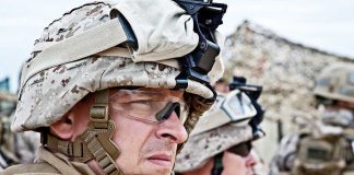 Two soldiers in military gear looking serious in an outdoor setting