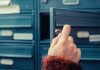 A hand holding a key, opening a blue mailbox drawer