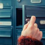 A hand holding a key, opening a blue mailbox drawer