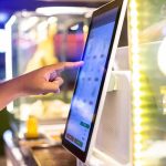 A hand interacting with a touchscreen menu in a restaurant