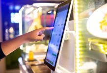 A hand interacting with a touchscreen menu in a restaurant