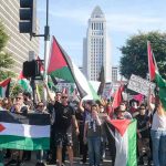 Protesters holding signs and flags in a public square.