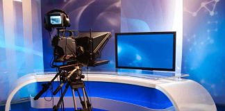 Television studio setup with a camera and monitor on a modern desk