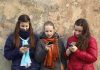 Three teenagers using smartphones while standing against a textured wall