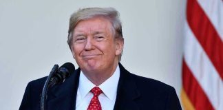 Trump Charms PM – Lands MAJOR Deal! Man in suit and tie speaking at podium.