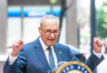 Dems  FREEZES Troop Paychecks – Cash Their Own! Man in suit and glasses speaks passionately at podium.