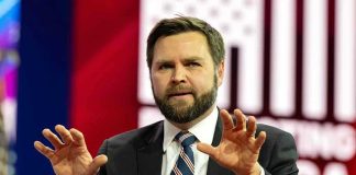 Vance Under Fire – Shocking Comments About Wife! Man in suit gesturing with hands on stage.