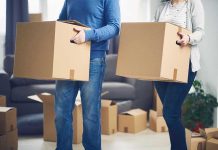 MASS EXIT: Residents FLEEING State! Two people carrying cardboard boxes indoors.