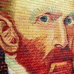 Colorful mural of a mans face on a brick wall