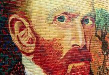 Colorful mural of a mans face on a brick wall