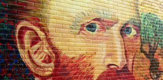 Colorful mural of a mans face on a brick wall