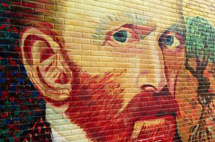 Colorful mural of a mans face on a brick wall