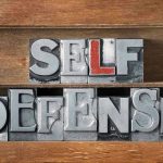 Homeowner Fires BLINDLY – Wrong Address TRAGEDY Metallic block letters spelling SELF DEFENSE on wooden shelves.