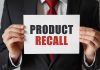 Product Recall sign held by person in suit.