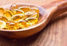 Golden omega-3 capsules in a wooden spoon