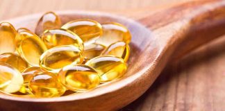 Yellow Urine EXPOSES Vitamin Industry Scam Golden omega-3 capsules in a wooden spoon