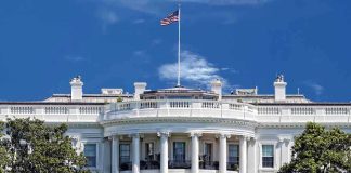 White House DESTROYS Socialist Agenda With Perfect Timing The White House with the American flag flying against a blue sky