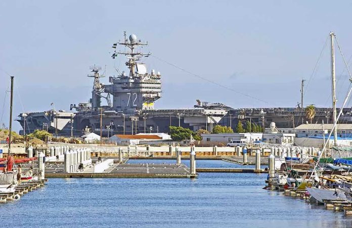 A large naval aircraft carrier docked in a harbor with smaller boats in the foreground