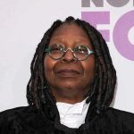 Whoopi’s TRUMP Blunder Sparks Media Firestorm Person with dreadlocks and round glasses, smiling slightly.