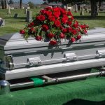 Silver casket with red roses in a cemetery.