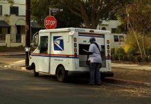 Postal Worker’s SHOCKING Christmas Theft Scheme CAUGHT! USPS mail carrier at truck near stop sign.