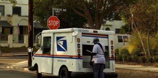 Postal Worker’s SHOCKING Christmas Theft Scheme CAUGHT! USPS mail carrier at truck near stop sign.