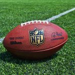 NFL Star CHARGED – Felony ROCKS Playoffs NFL football on a green field.