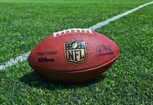 NFL Star CHARGED – Felony ROCKS Playoffs NFL football on a green field.