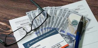 Severe Medicaid FRAUD – Dead People Paid Billions! Medicare card glasses pen money on wooden table