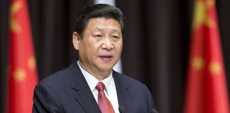 A political leader delivering a speech at a podium with national flags in the background