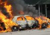 A car engulfed in flames with thick smoke billowing into the air